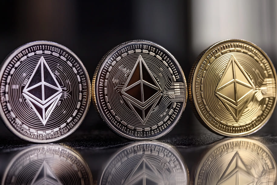 Three Ethereum coins, two silver and one gold, standing upright on a reflective surface, symbolizing the power of blockchain technology and decentralized finance in 2025. A visual representation of cryptocurrency investment, Ethereum trading, and digital asset innovation.